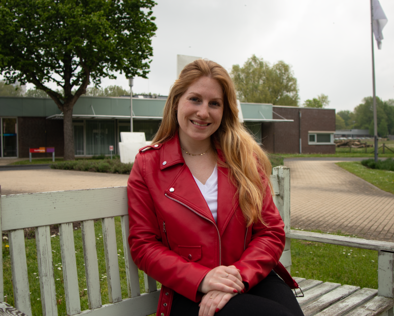 =Meisje zit op bankje voor hoofdingang